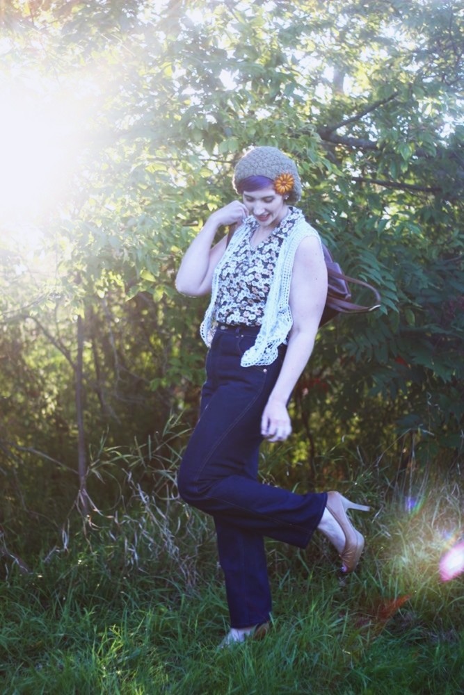 1970s Inspired Outfit: Floral blouse, white lace vest, high waisted dark wash denim, high heels, mini brown backpack