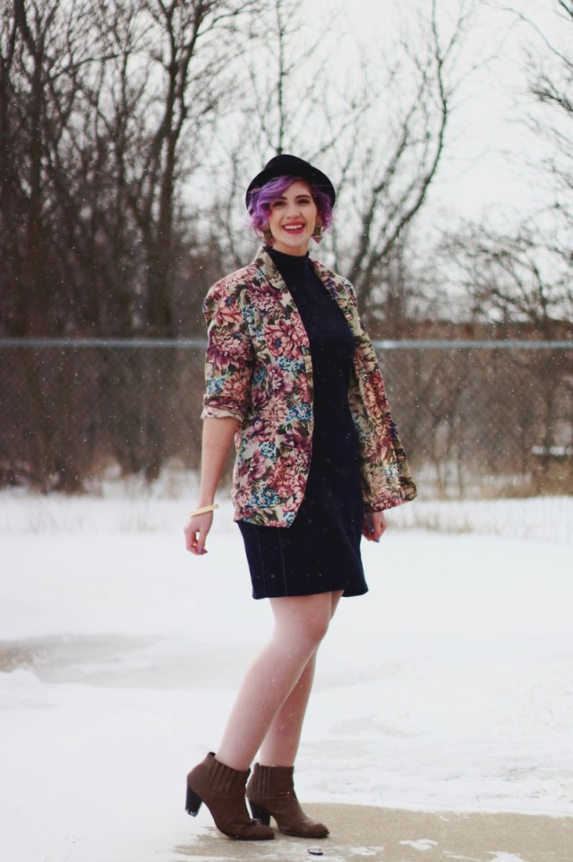 Pretty In Pink inspired volcanic ensemble: Black mockneck bodycon dress, vintage floral blazer, black pork pie hat, 80s-era statement earrings, beige booties
