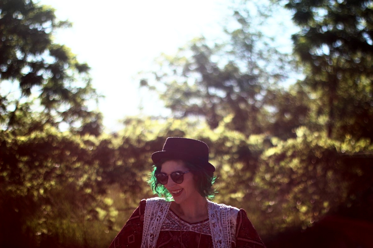 1 Top, 2 Music Festival Outfits | theoutfitrepeater.com white female standing in a sunny, grassy field. wearing a boho style red peasant blouse and black pork pie hat