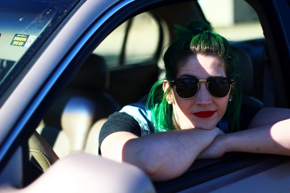 Outfit details: black sunglasses, ColourPop ultra matte lip color in Creeper, green Arctic Fox hair, sitting in a car waiting for a roadtrip