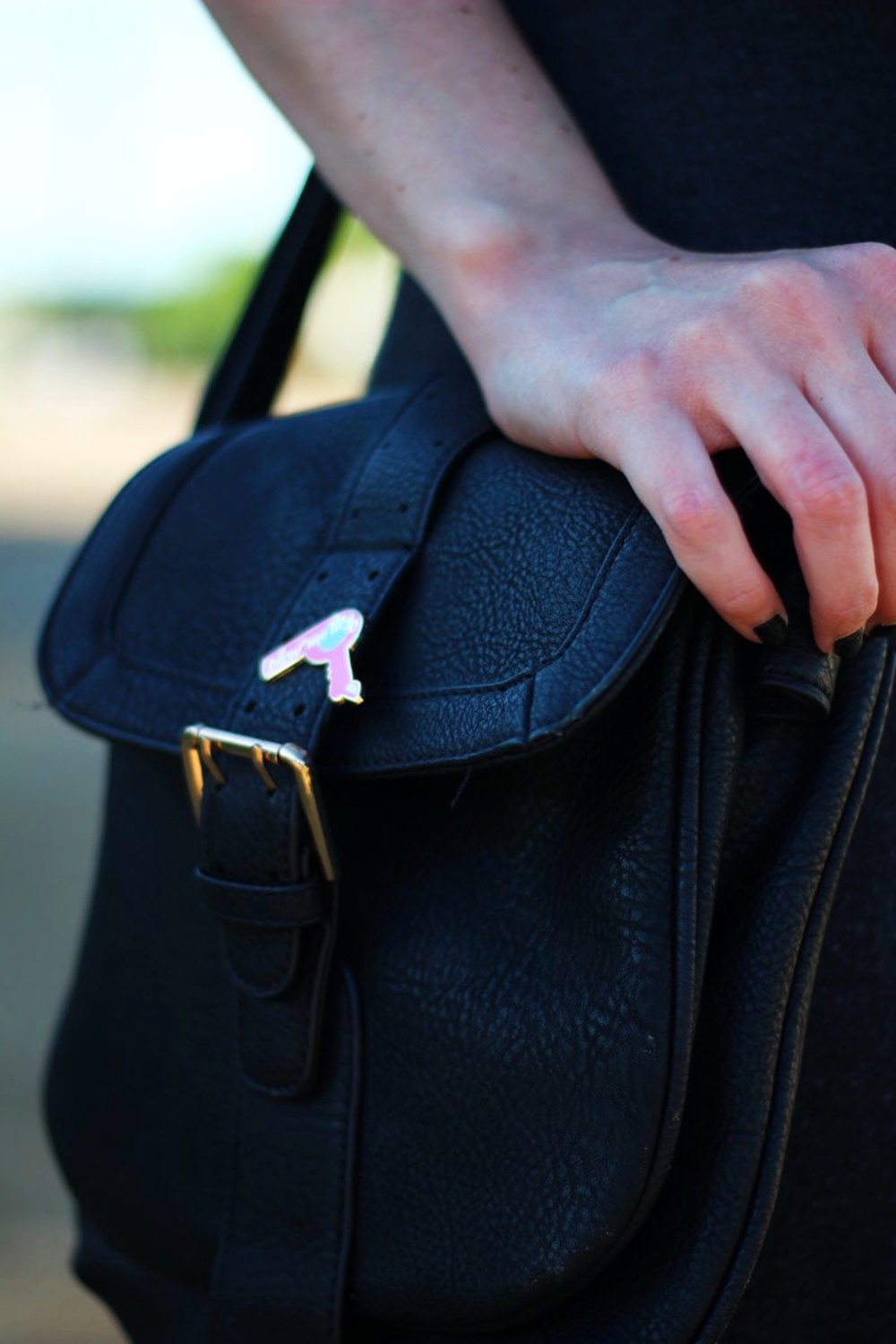 Summer road trip outfit details: thrifted black cross body bag and Darling Distraction enamel pin hot pink blowdryer