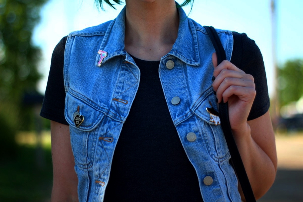 Outfit: light wash denim vest, thrifted crossbody bag, Darling Distraction enamel pins