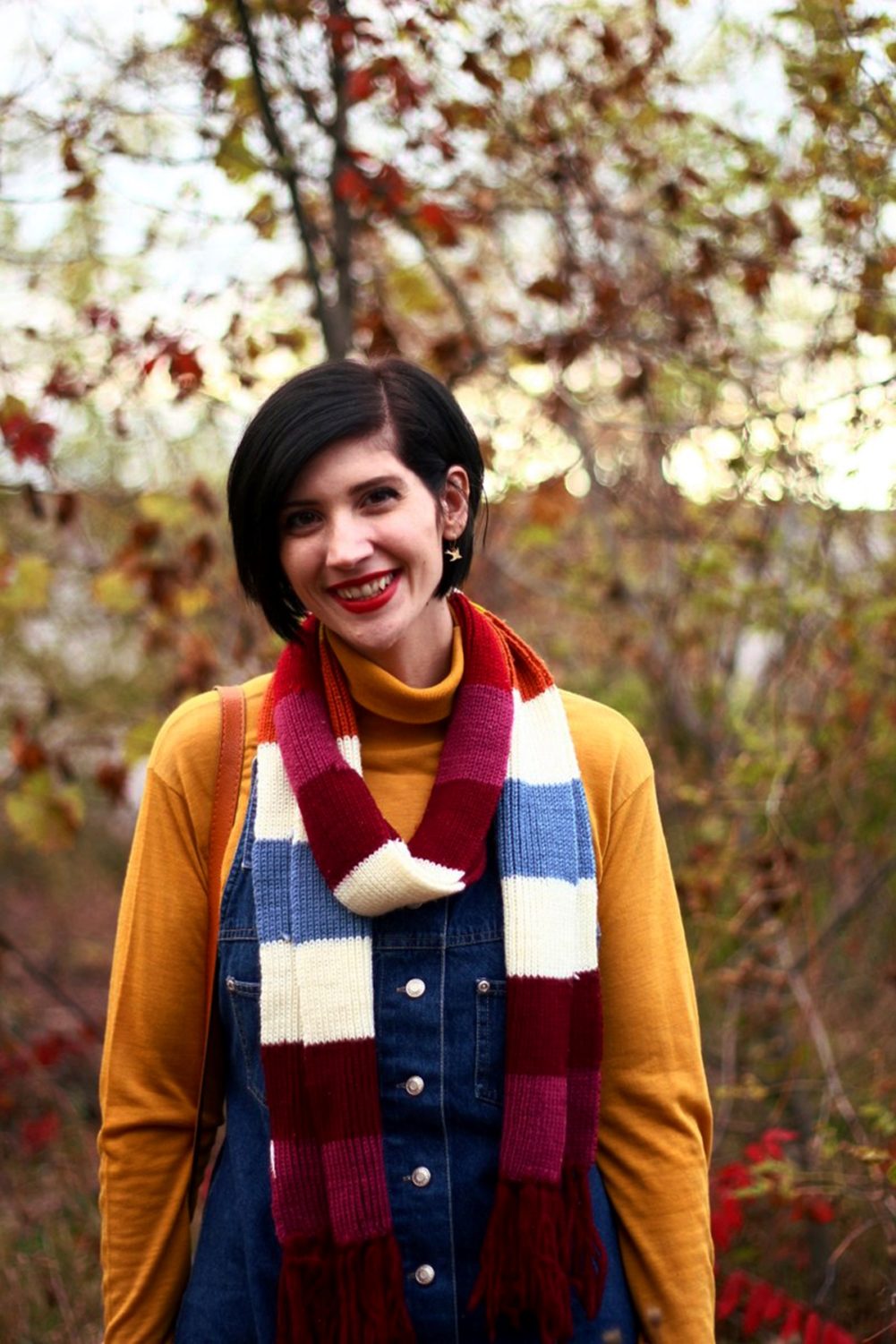 Outfit: Mustard yellow turtleneck, denim overall dress, multi-colored striped scarf, red lipstick