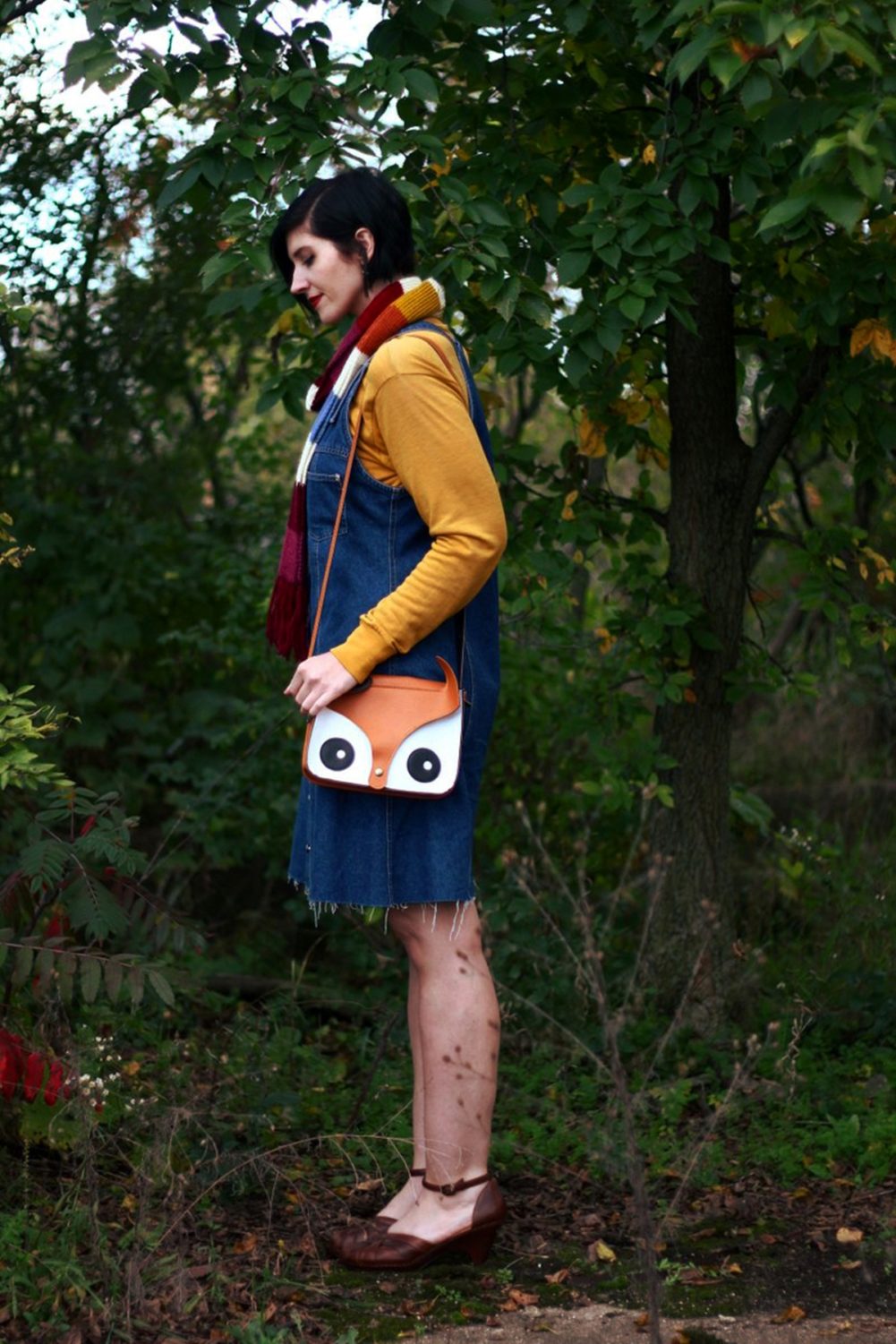 Outfit: Mustard yellow turtleneck, denim overall dress, multi-colored striped scarf, red lipstick, orange fox handbag, brown platforms