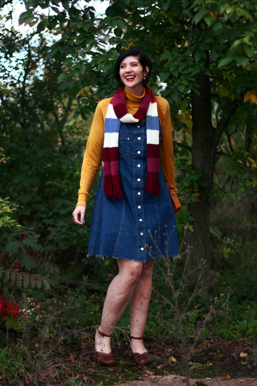 Outfit: Mustard yellow turtleneck, denim overall dress, multi-colored striped scarf, red lipstick, orange fox handbag, brown platforms