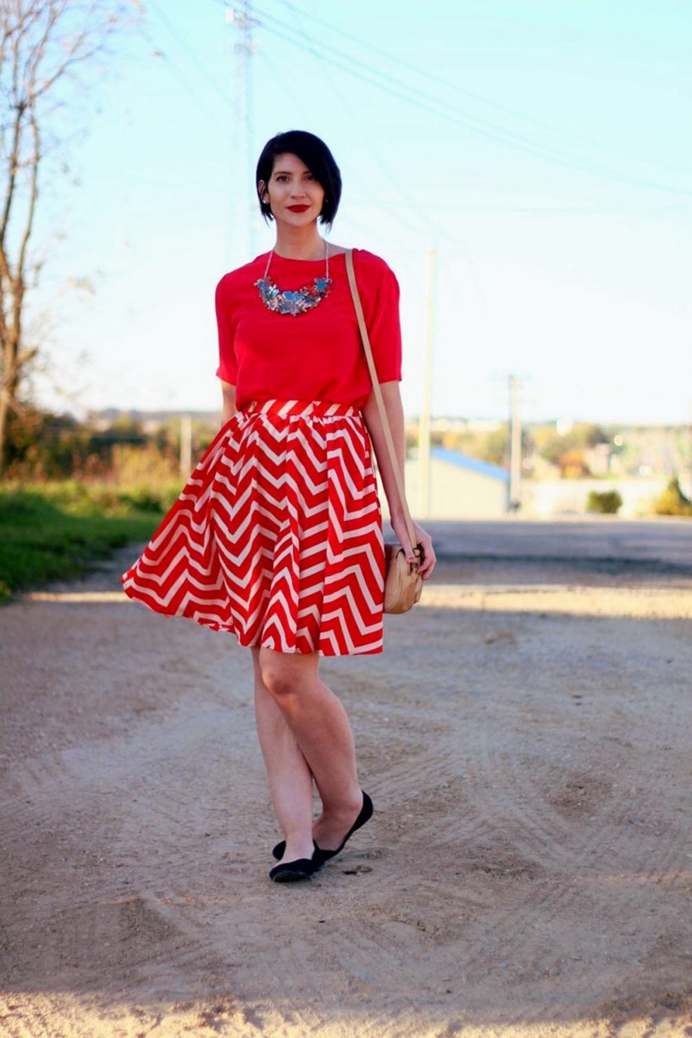 Outfit: Vintage red top, DIY puzzle piece necklace, red lipstick, thrifted orange chevron skirt, beige cross body purse, black flat shoes. 