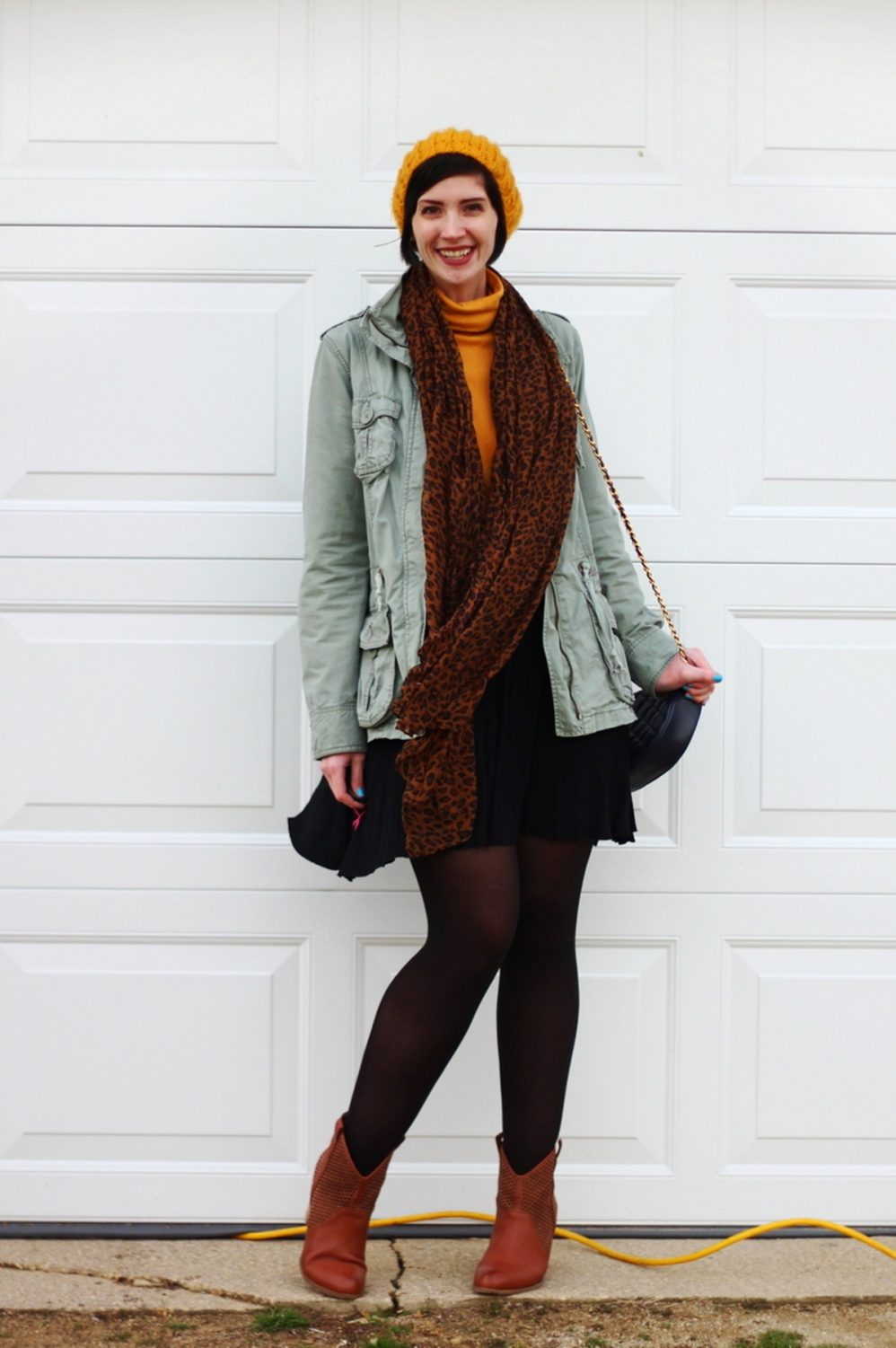 Outfit: mustard yellow turtleneck, olive green utility jacket, leopard print scarf, yellow knit hat, black skater skirt, black tights, cognac colored boots, navy blue quilted purse