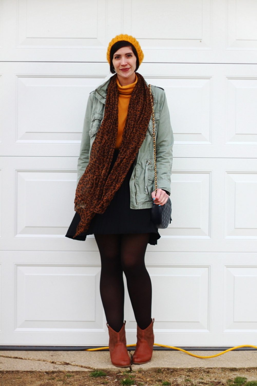 Outfit: mustard yellow turtleneck, olive green utility jacket, leopard print scarf, yellow knit hat, black skater skirt, black tights, cognac colored boots, navy blue quilted purse