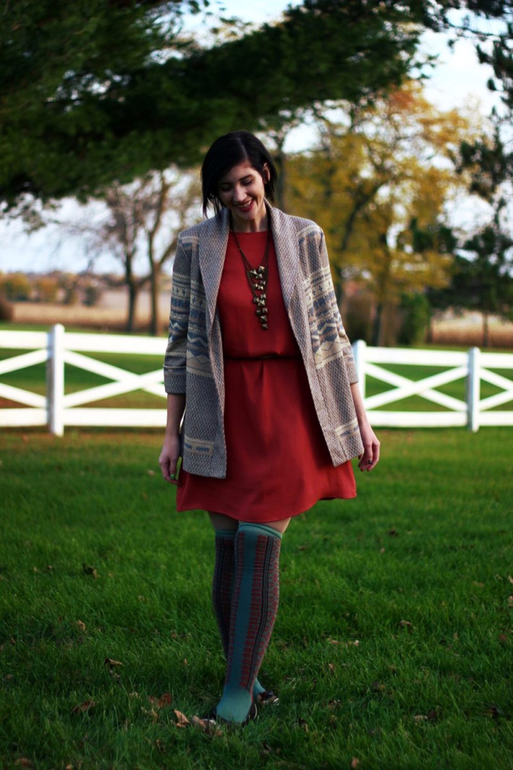 Outfit: Orange dress, beige belt, bronze necklace, patterned cardigan, otk colorful socks, brown flats 