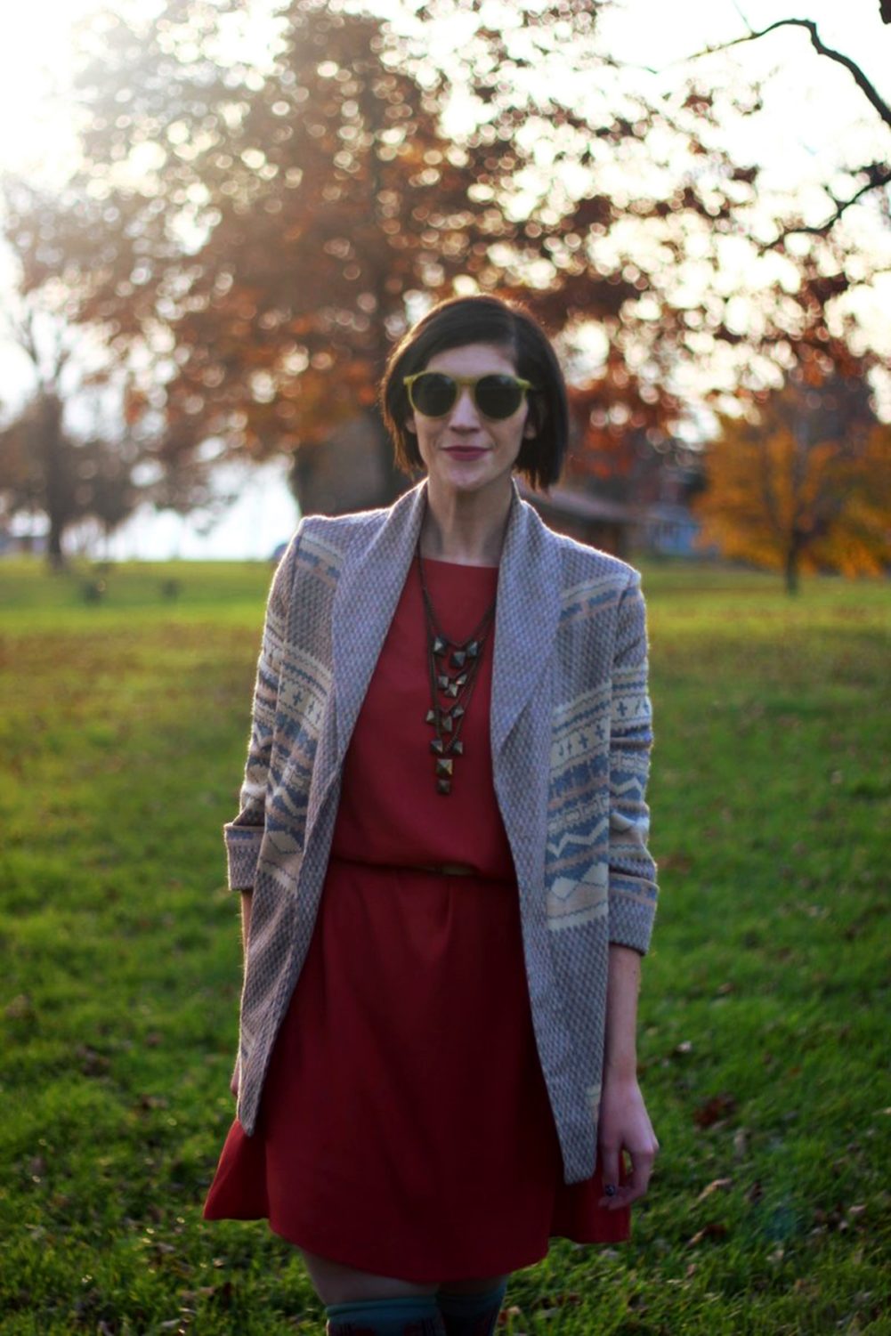 Outfit: Orange dress, beige belt, bronze necklace, patterned cardigan