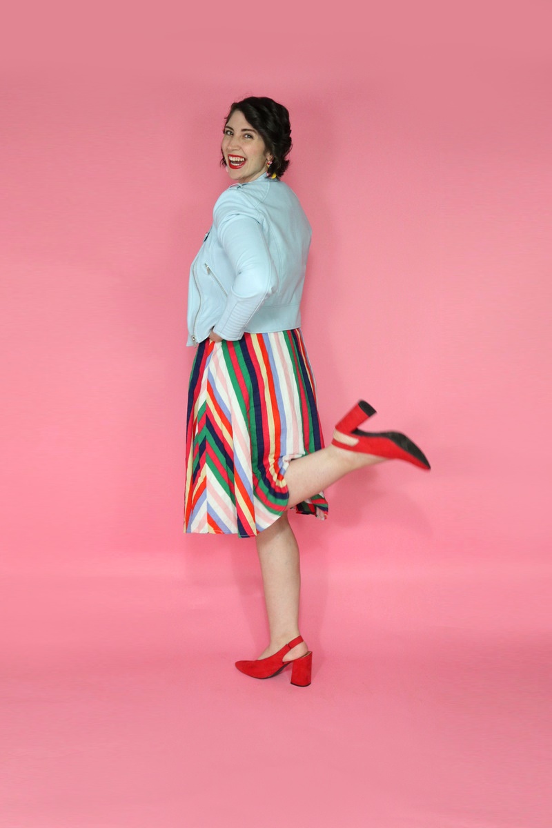 3 Questions That Will Change The Way You Look At Your Closet | www.theoutfitrepeater.com Hannah is wearing a thrifted graphic tee with a blue moto jacket on top, rainbow striped knee length skirt on the bottom, and red high heels