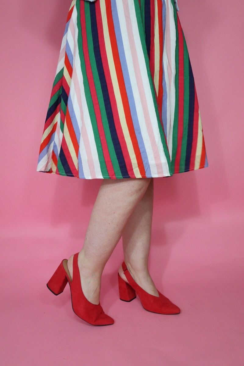 Hannah is wearing a thrifted knee length skirt on the bottom and red high heels