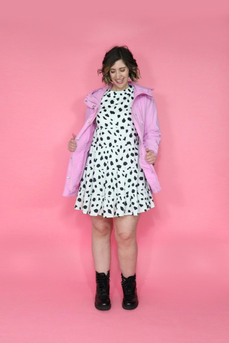 hannah's smiling and looking down in a polka dot dress and pink rain coat