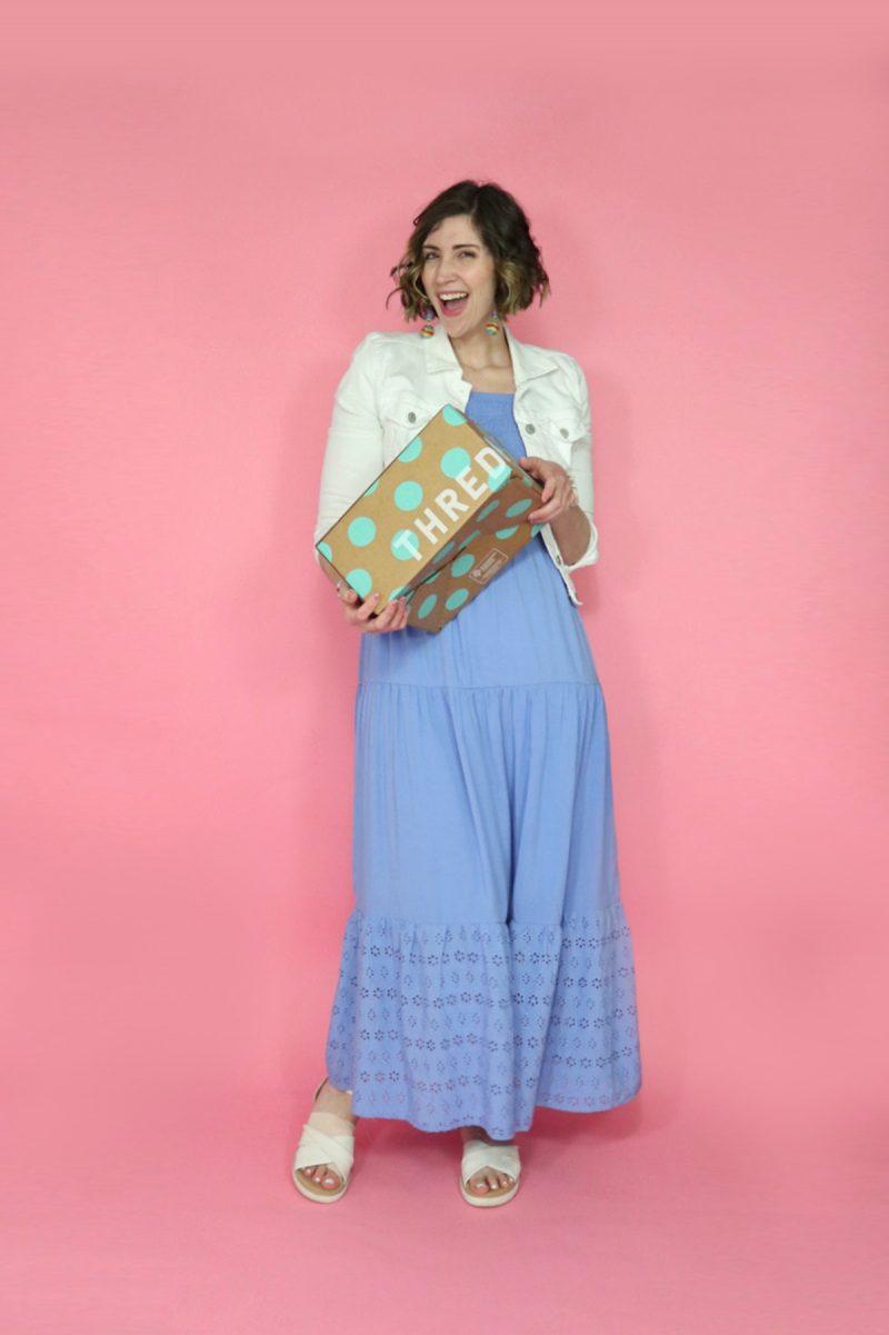 hannah wears a long blue dress, holds a brown and teal thredUP shipping box