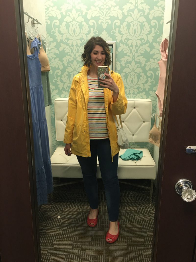 Outfit Photo Dump: What I Wore At Work (In A Clothing Store!) | www.theoutfitrepeater.com hannah is standing in front of a mirror. she's wearing a rainbow striped top, yellow rain coat, blue jeans, and red ballet flats