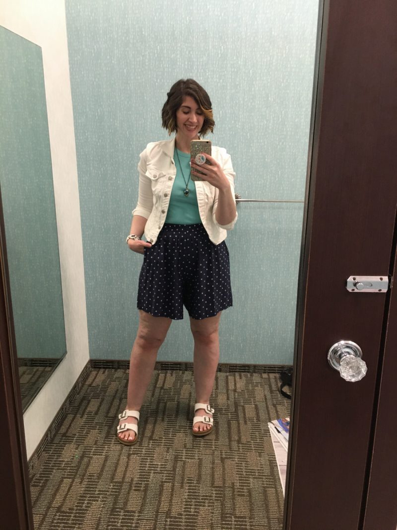 Outfit Photo Dump: What I Wore At Work (In A Clothing Store!) | www.theoutfitrepeater.com hannah is standing in front of a mirror. she's wearing a turquoise tank top, white denim jacket, blue polka dot shorts, and white sandals