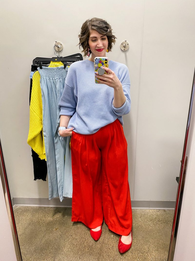 hannah rupp is dressed in brightly colored clothing taking a picture in a thrift store fitting room