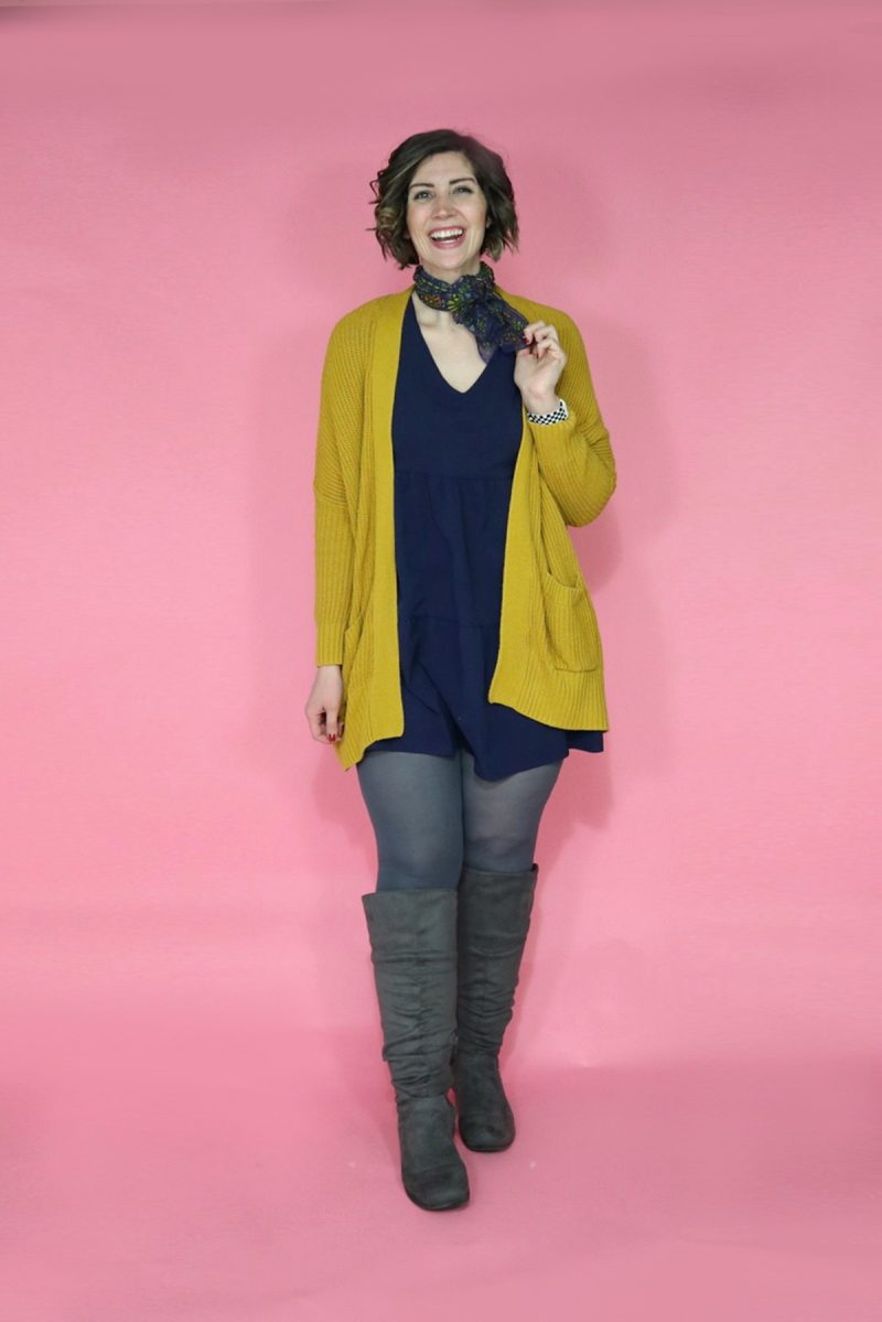 TikTok Outfit Challenge: My Followers Pick My Outfit For 1 Week | theoutfitrepeater.com hannah is wearing a blue scarf around her neck, a black mini dress, a yellow cardigan, gray tights, and tall gray boots