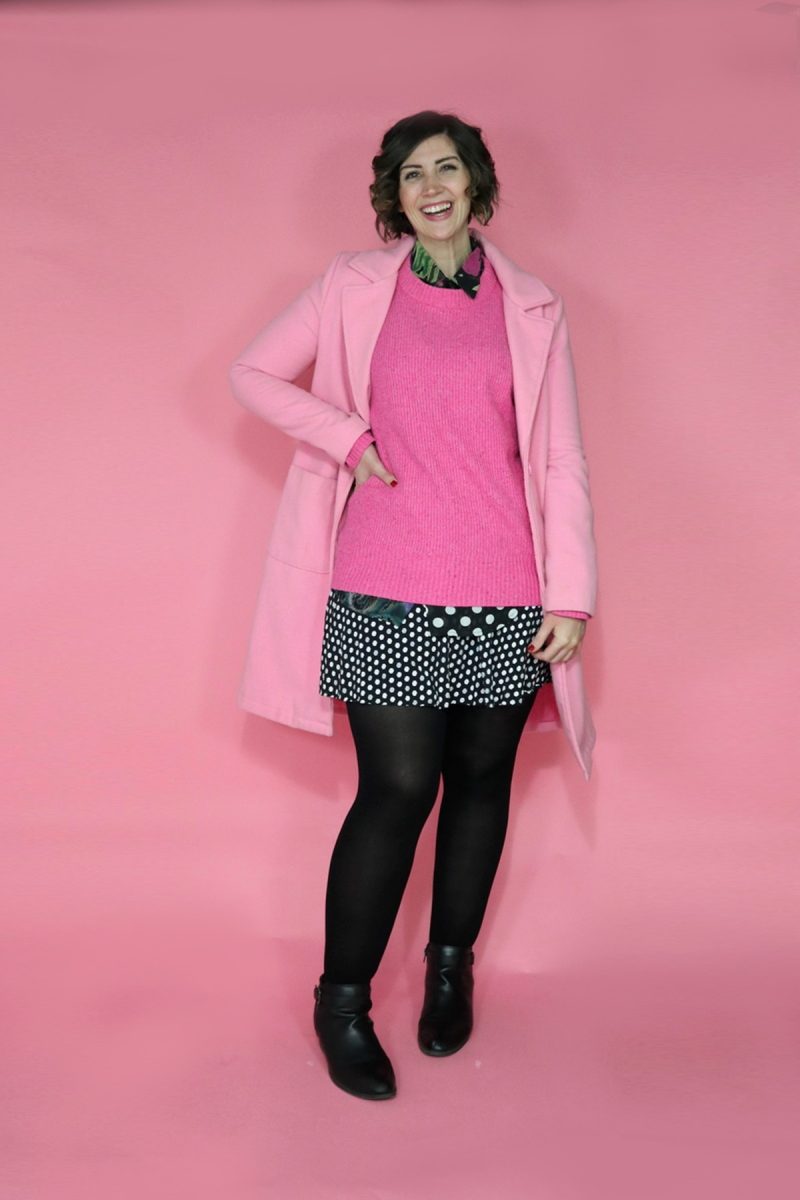 TikTok Outfit Challenge: My Followers Pick My Outfit For 1 Week | theoutfitrepeater.com hannah is wearing a layered outfit which is a polka dot top and skirt with a pink sweater on top and a pink coat. she has black accessories on.