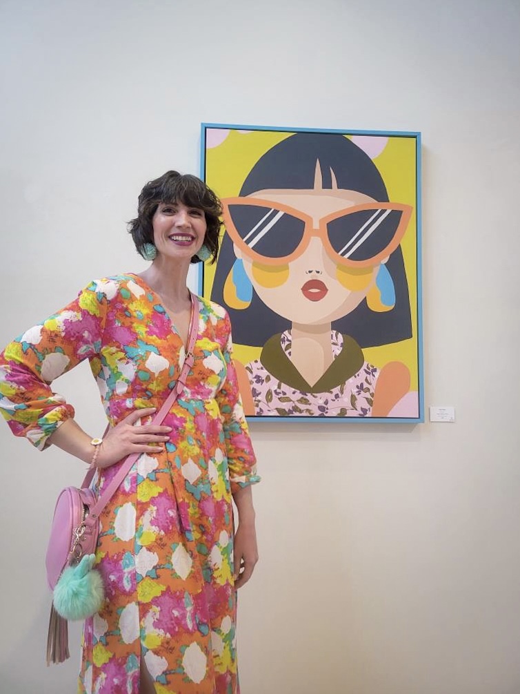 hannah is wearing a colorful maxi dress and pink crossbody purse. she's standing next to an Efflorescence by Emma Daisy painting at Monroe Arts Center in Monroe, Wisconsin