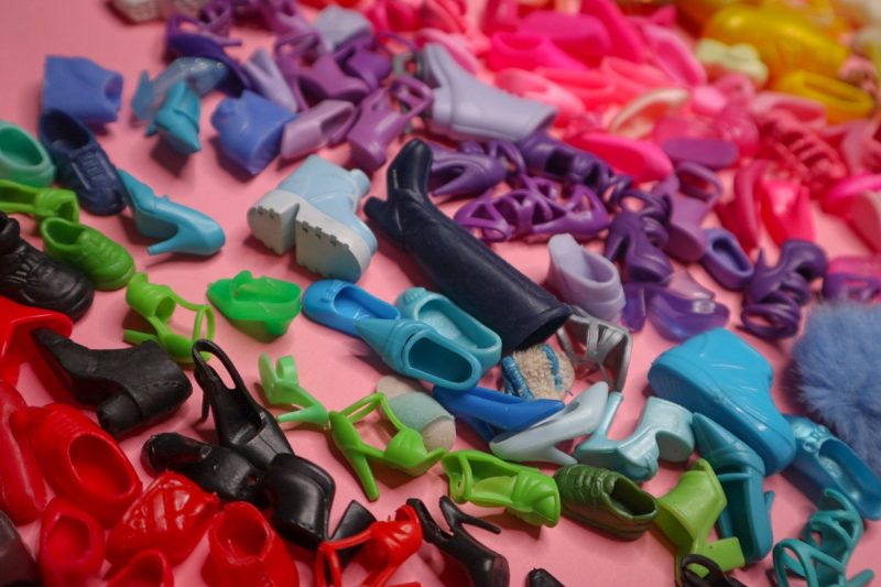 8 Simple Barbie Shoe Jewelry & Accessories You Can Make At Home! | www.theoutfitrepeater.com a colorful arrangement of vintage plastic Barbie doll shoes spread out on pink paper
