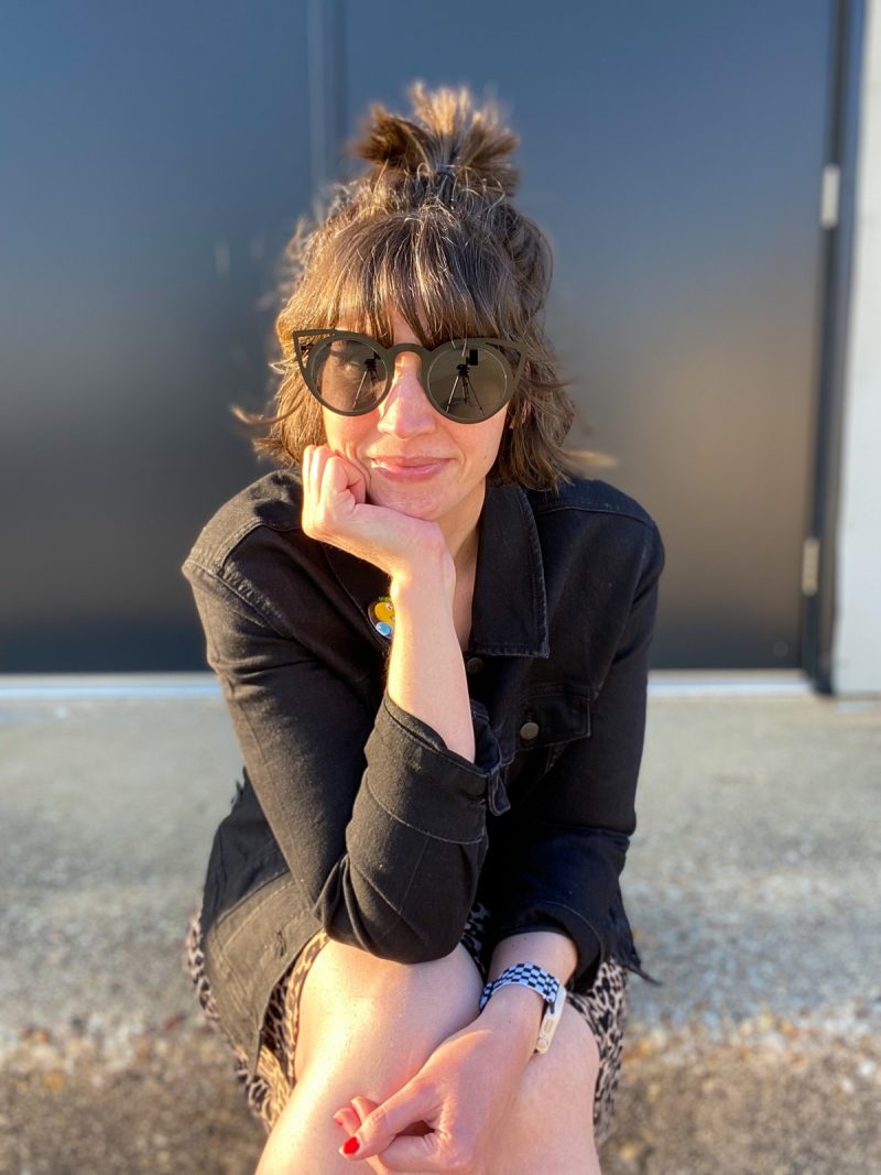 Wearing All Black Is Boring, Here's How To Make It Better | www.theoutfitrepeater.com hannah rupp is a white female with short brown hair. she's wearing dark sunglasses, a black denim jacket, yellow tank top, and leopard print skirt.