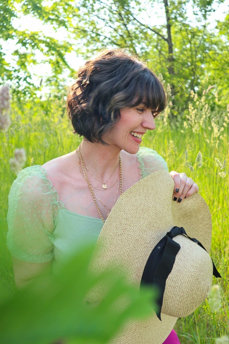 This Outfit Will Convince You To Wear Those Fancy Clothes You've Been Saving | www.theoutfitrepeater.com hannah rupp is in a bright, green field. she's wearing a mint green blouse, floppy hat, and gold jewelry.