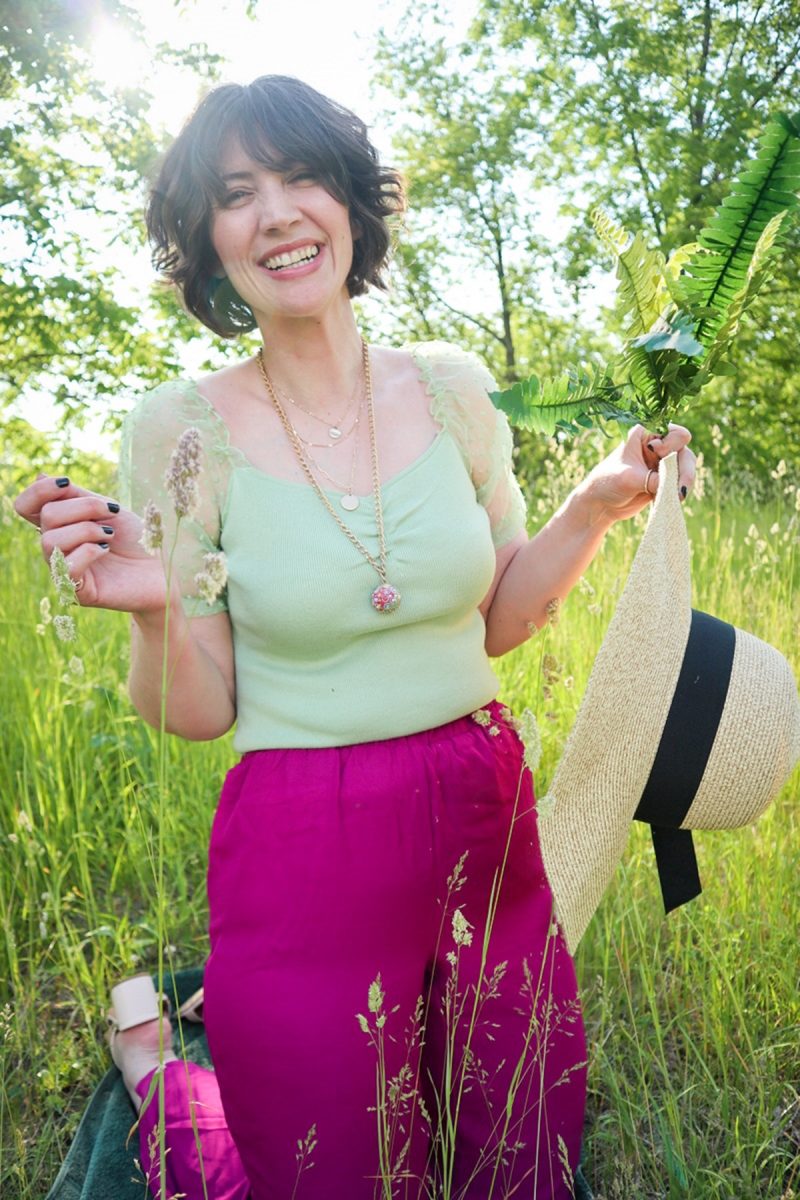 This Outfit Will Convince You To Wear Those Fancy Clothes You've Been Saving | www.theoutfitrepeater.com hannah rupp is in a bright, green field. she's wearing a mint green blouse, floppy hat, magenta palazzo pants, straw bag, and gold jewelry.