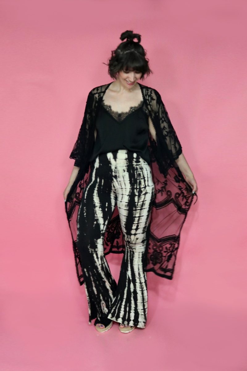 A thredUP Summer Thrift Haul | What I'm Keeping + Returning | www.theoutfitrepeater.com hannah is standing in front of a pink background. she's wearing a black cami, black lace kimono, black and white tie dye pants and black platform sandals.