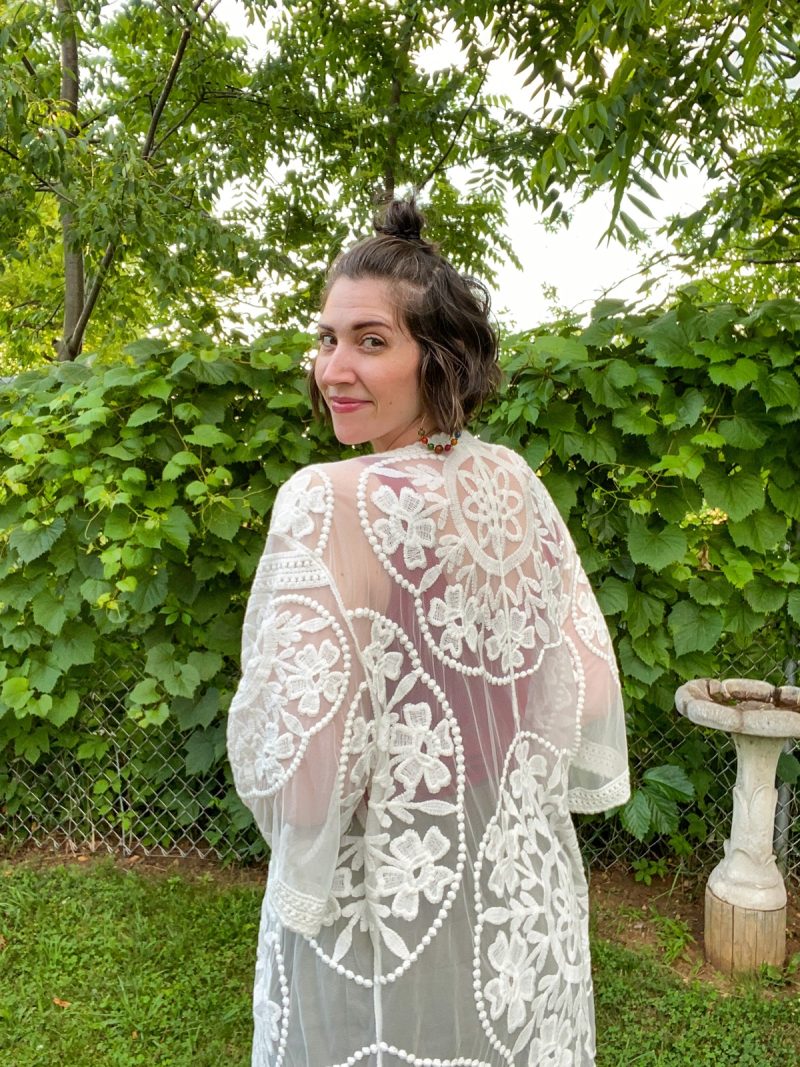 The Perfect Outfit For Christmas In July | www.theoutfitrepeater.com hannah is standing in a yard surrounded by greenery. she's wearing lacey white kimono.