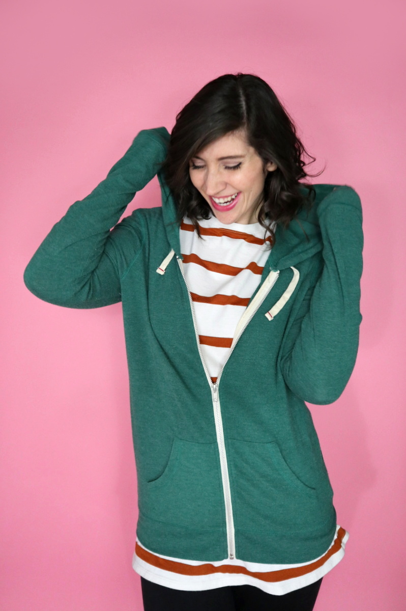 10 Essential Outfits You Should Always Have In Your Closet | theoutfitrepeater.com White female with short brown hair laughing wearing an orange and white striped shirt with a green zip hooded sweatshirt