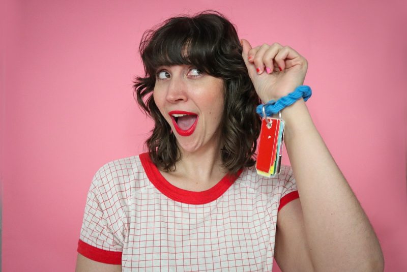 Budget-Friendly Personal Color Analysis: Affordable Ways to Find Your Palette | www.theoutfitrepeater.com white female with brown curly hair, pink paper background, holding up a stack of paint samples