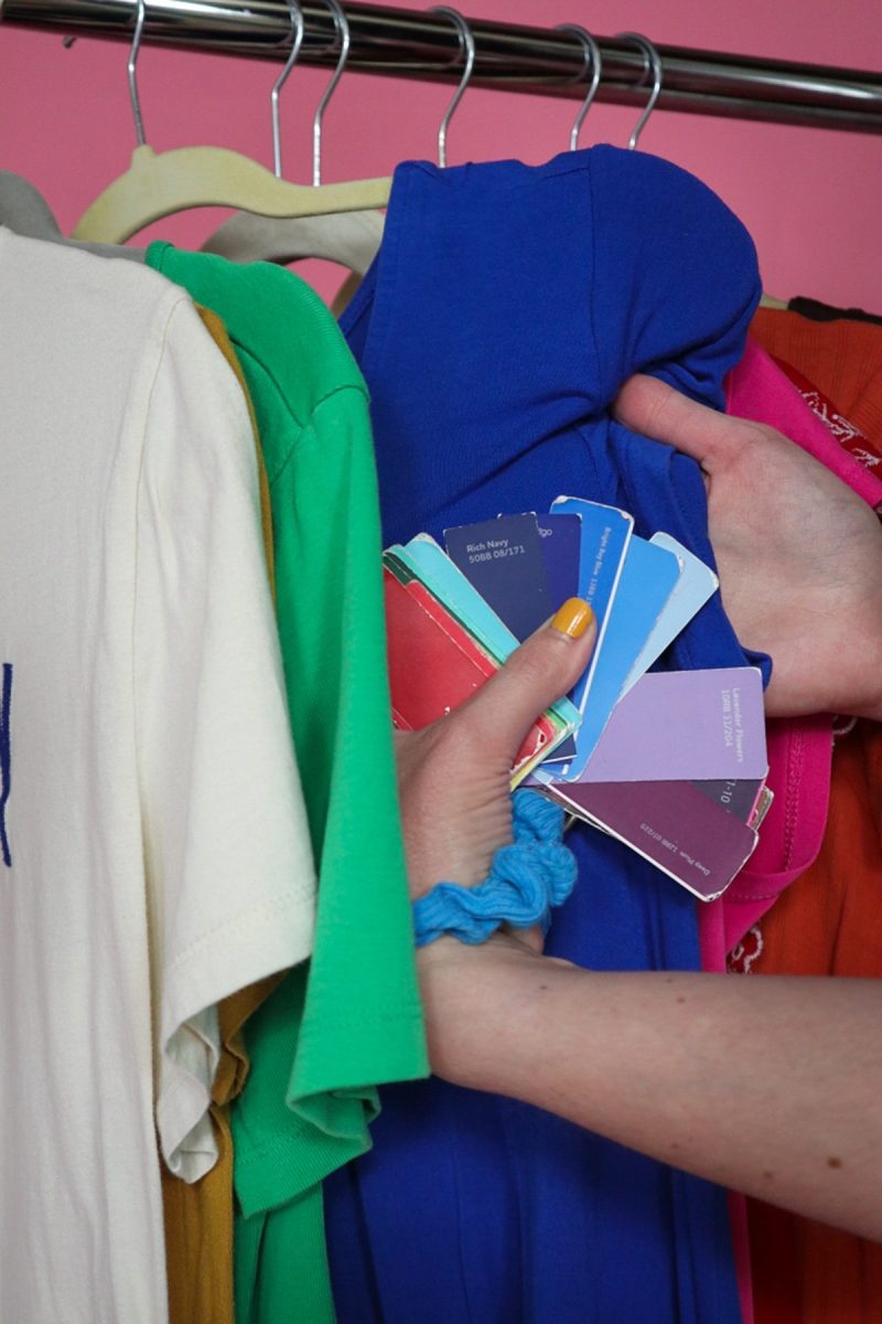 Budget-Friendly Personal Color Analysis: Affordable Ways to Find Your Palette | www.theoutfitrepeater.com a hand is holding a fan of paint samples and comparing them to a rack of colorful clothes