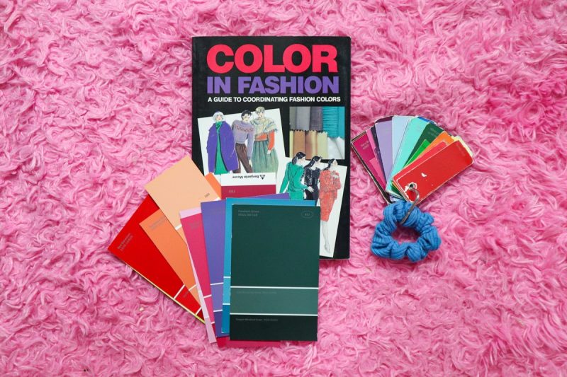 Budget-Friendly Personal Color Analysis: Affordable Ways to Find Your Palette | www.theoutfitrepeater.com a pink rug with a Vintage book titled Color in fashion, a stack of paint samples, paint samples on a key ring