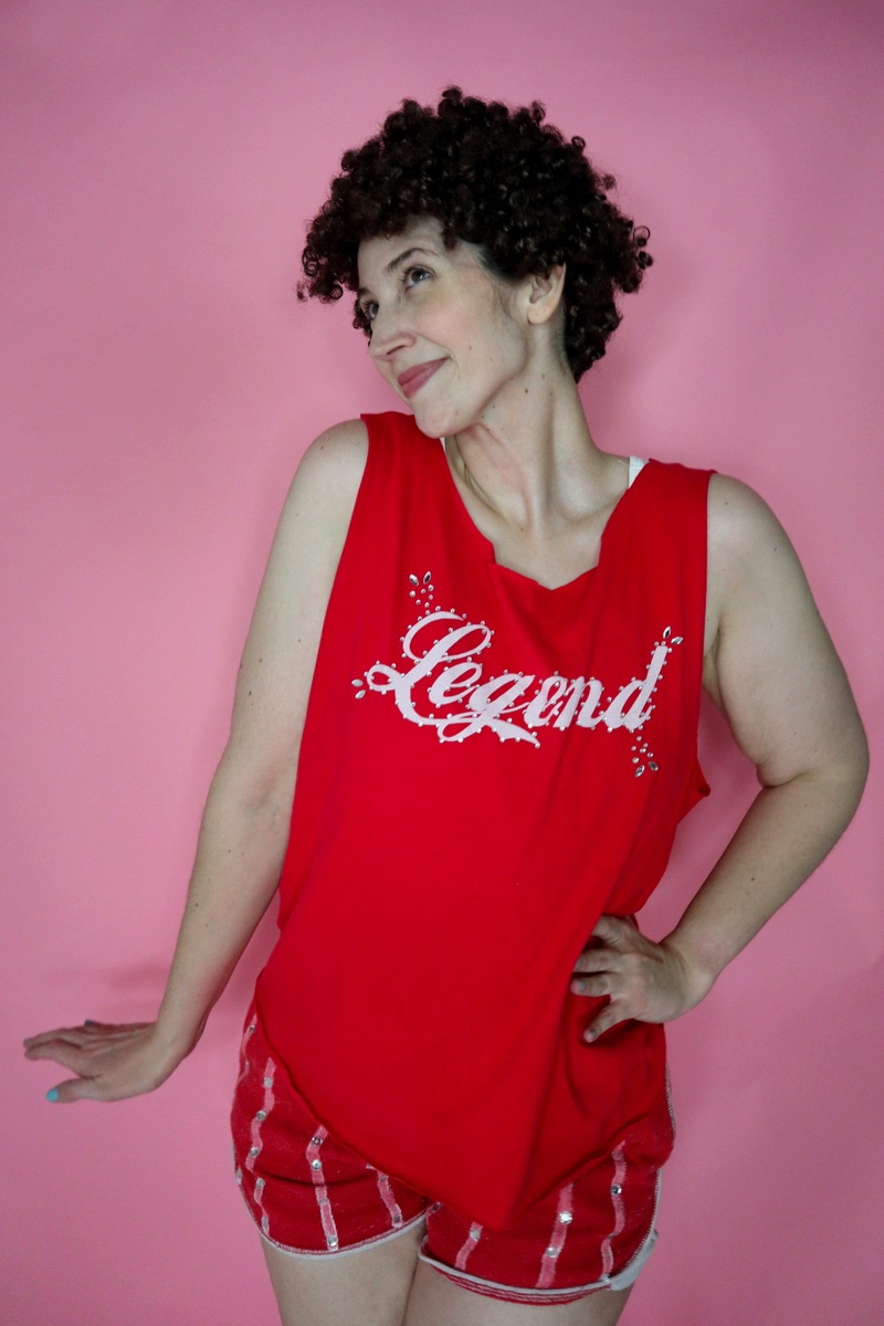 An Iconic Richard Simmons Halloween Costume | www.theoutfitrepeater.com thrifted richard simmons halloween costume red tank top, tiny striped dolphin shorts, curly hair, and white sneakers