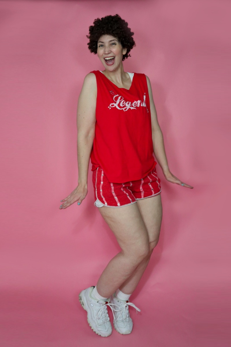 An Iconic Richard Simmons Halloween Costume | www.theoutfitrepeater.com thrifted richard simmons halloween costume red tank top, tiny striped dolphin shorts, curly hair, and white sneakers