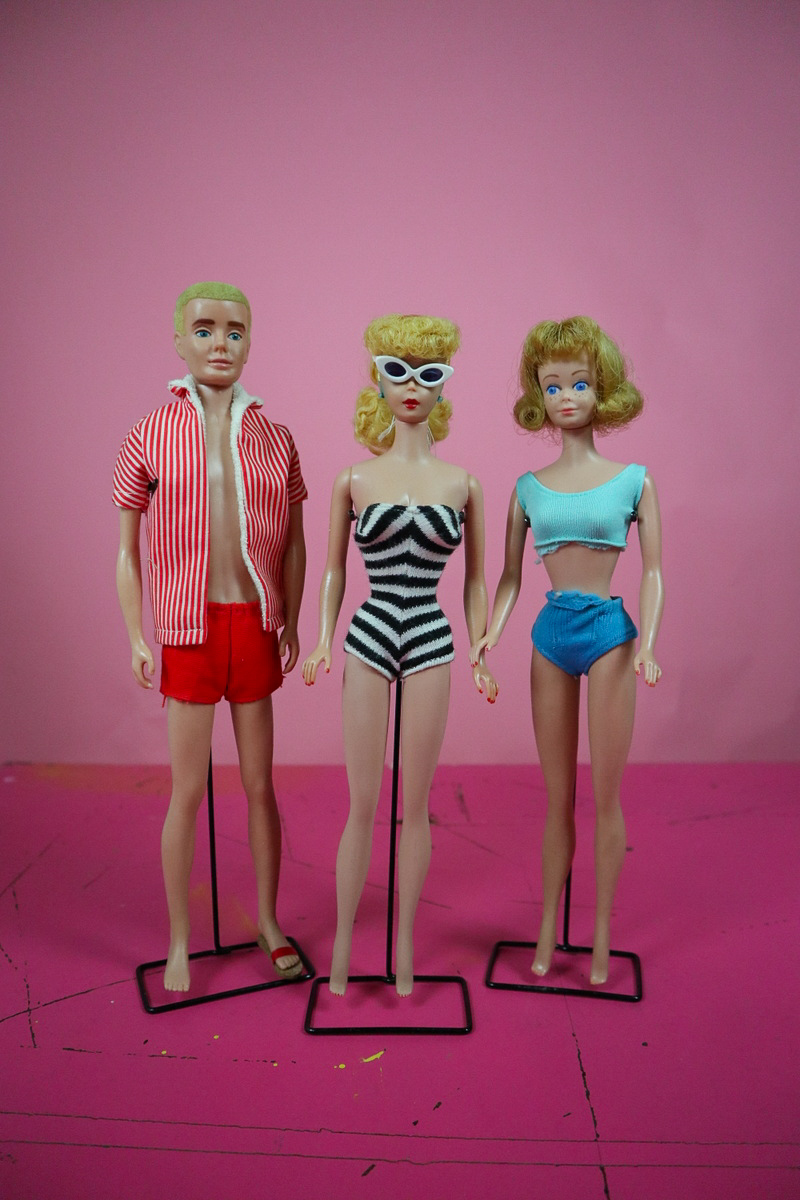 How I Saved Vintage Barbie Dolls from the Trash | www.theoutfitrepeater.com a pink background. in the foreground are three vintage Barbie dolls are the 1960s. Ken, Barbie, and Midge are all wearing their original swimsuit beach wear.