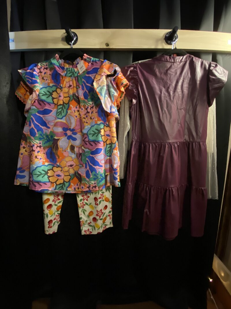 colorful clothes hanging up in a secondhand store fitting room