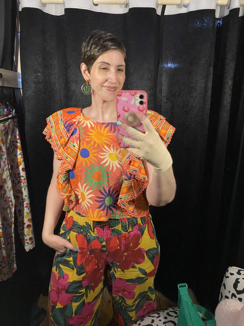 What I Thrifted vs. How I Styled It | www.theoutfitrepeater.com a white female with short brown hair takes a mirror selfie wearing a colorful blouse and printed pants